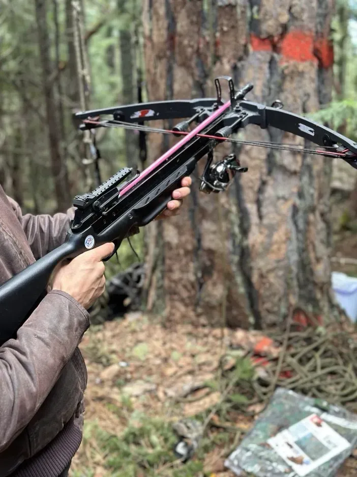 Forest Defender holding Crossbow used by forest defenders to set up a climb line and traverse line on very high branches